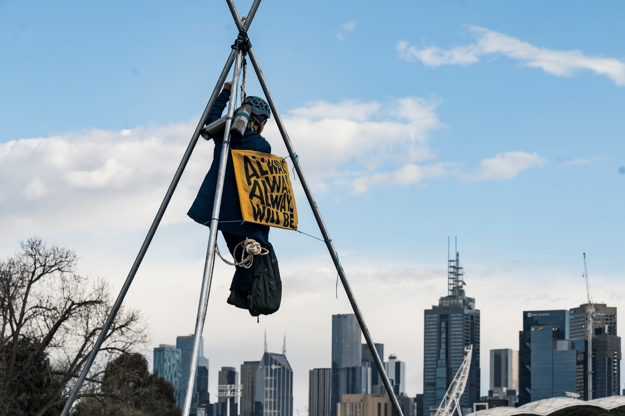 A protester suspends themselves atop a tripod on Punt Road Bridge in solidarity with Gunditjmara People opposed to seismic blasting