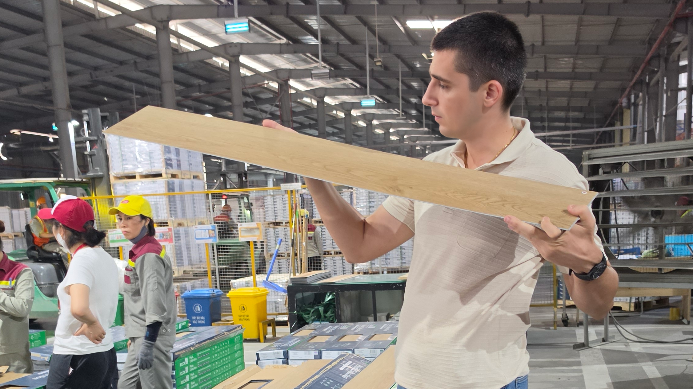 Nick reviewing a flooring sample on a factory production floor in Vietnam