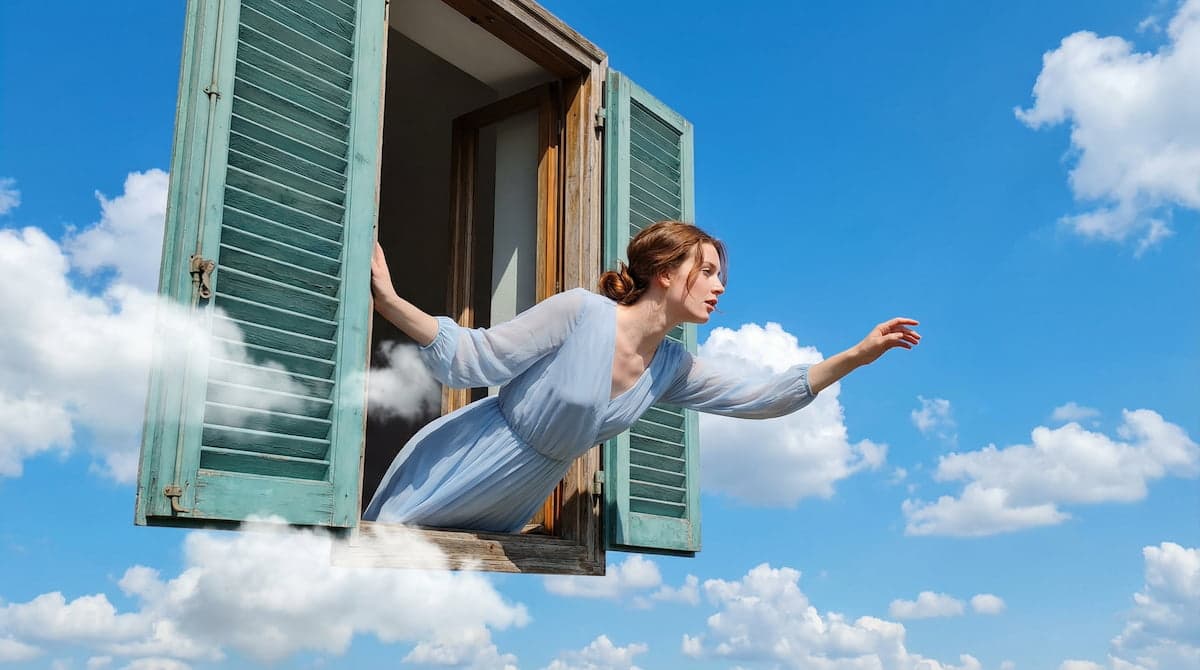 Woman in a pale blue dress leaning out of an open window with green shutters, floating in a cloudy blue sky