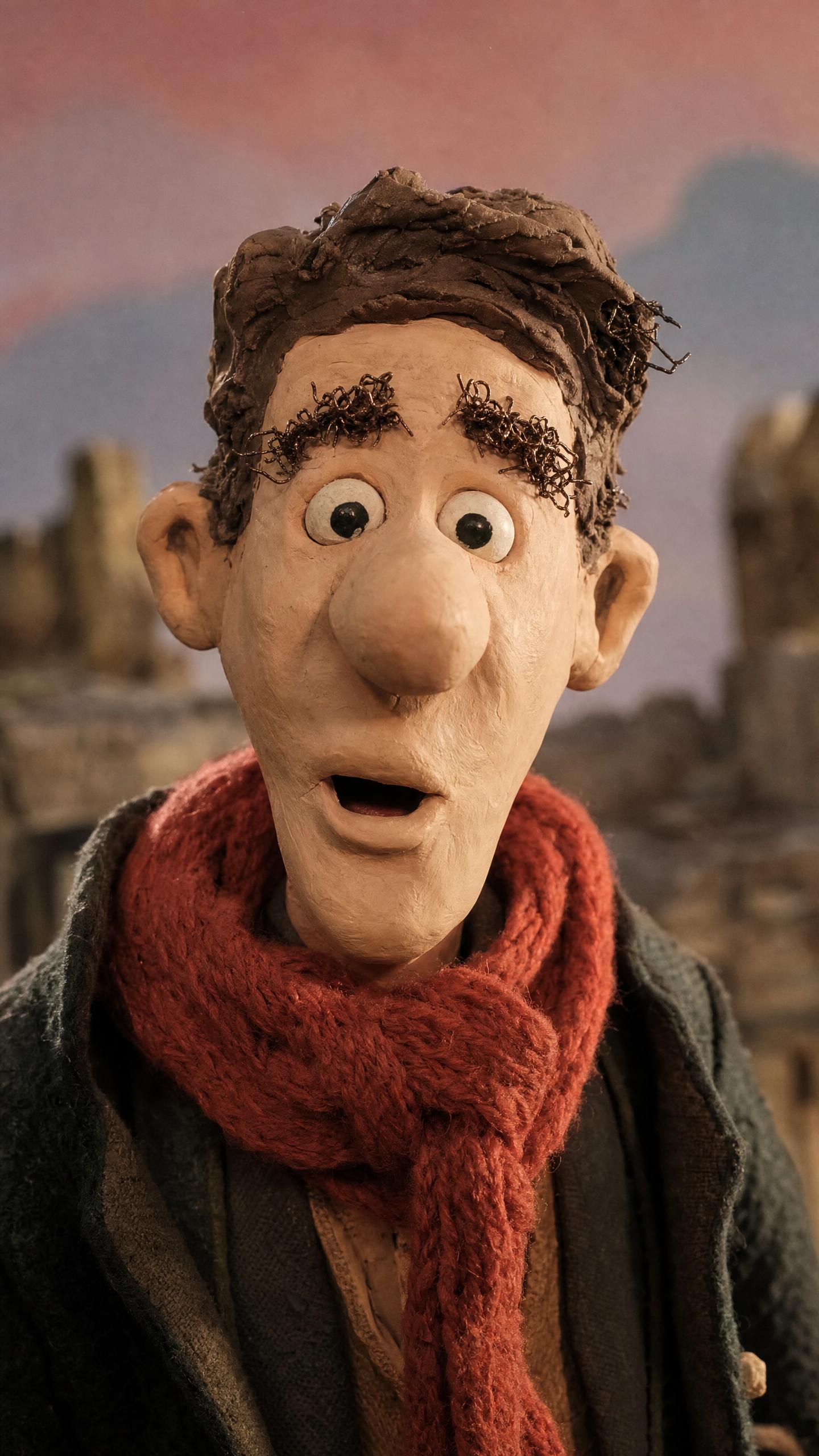 Close-up of a claymation man with bushy eyebrows and a red knit scarf, mouth open mid-sentence