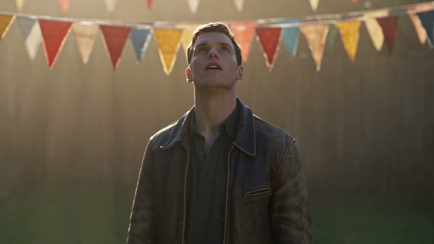 A man in a leather jacket reacting under fairground bunting