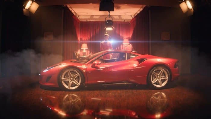 A red sports car lit in a smoke-filled screening room