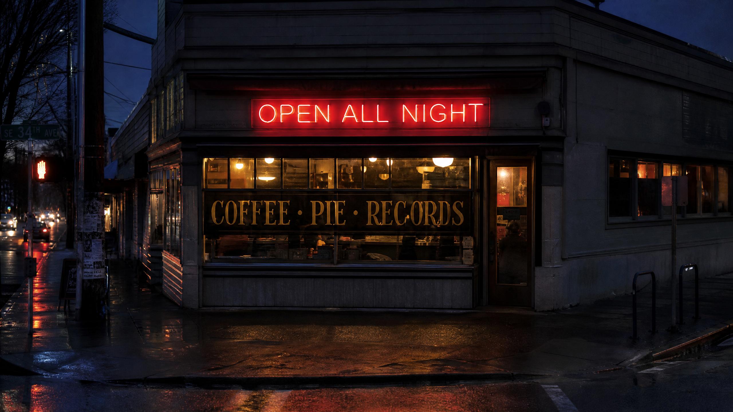 Corner diner at dusk with a neon sign reading OPEN ALL NIGHT and window lettering reading COFFEE, PIE, RECORDS