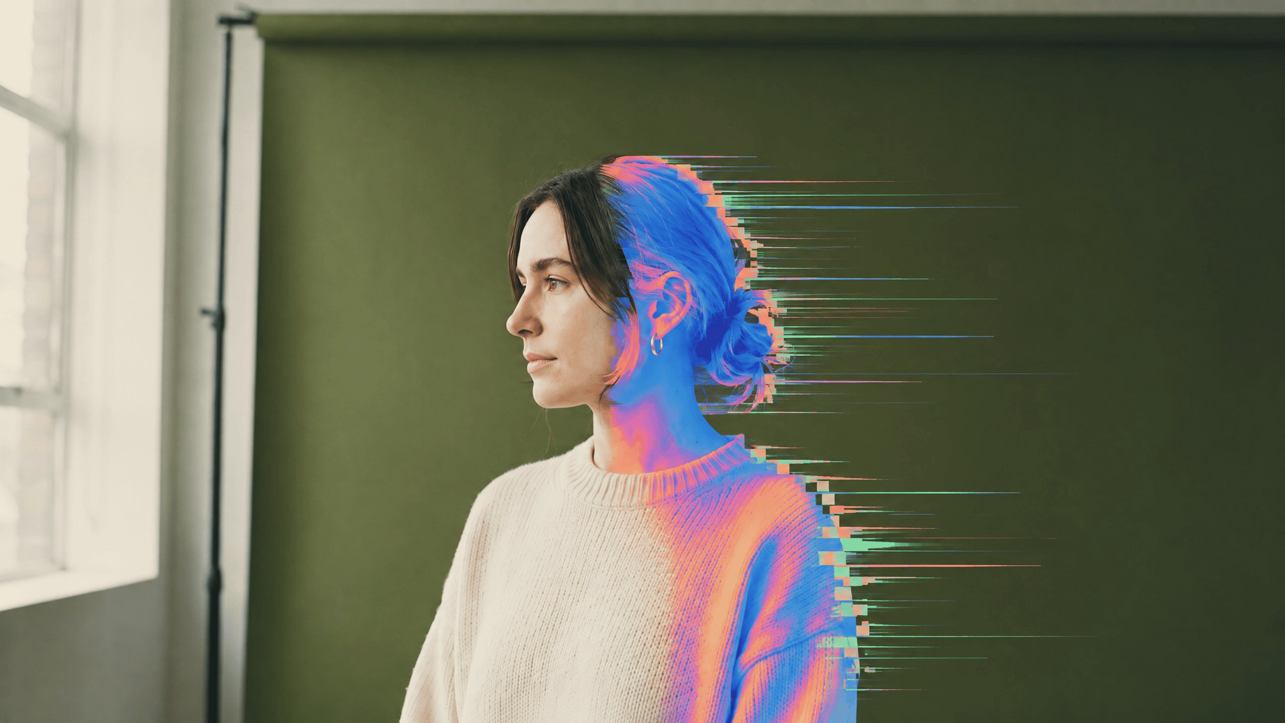 A woman by a window, with her portrait transitioning into colorful digital motion
