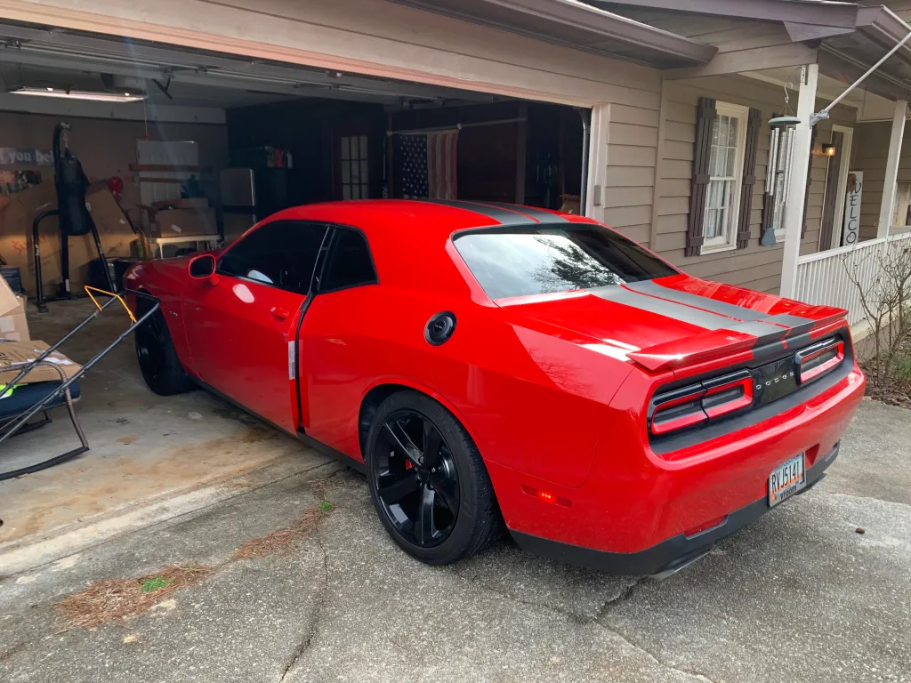 Red Dodge Challenger with racing stripes and dark window tint