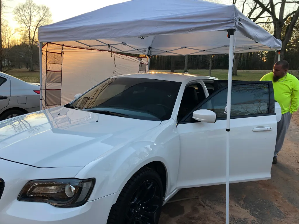 White Chrysler 300 getting tinted under a mobile canopy
