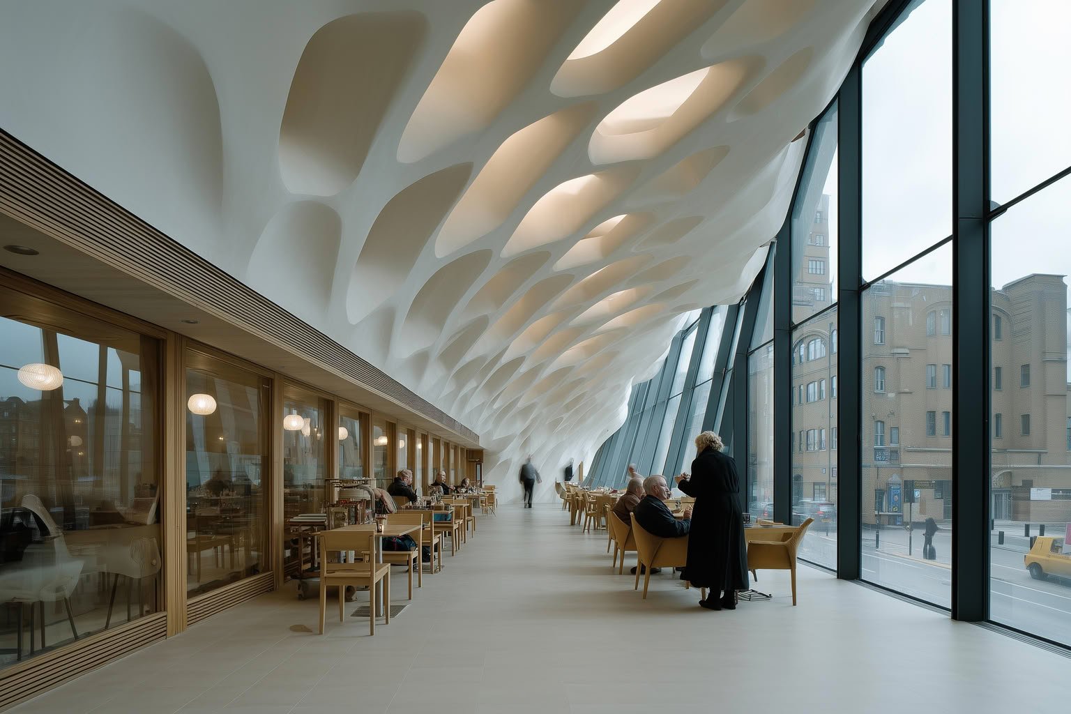 Modern cafe interior with an organic white sculpted ceiling, floor-to-ceiling glass windows, and warm wood dining areas.