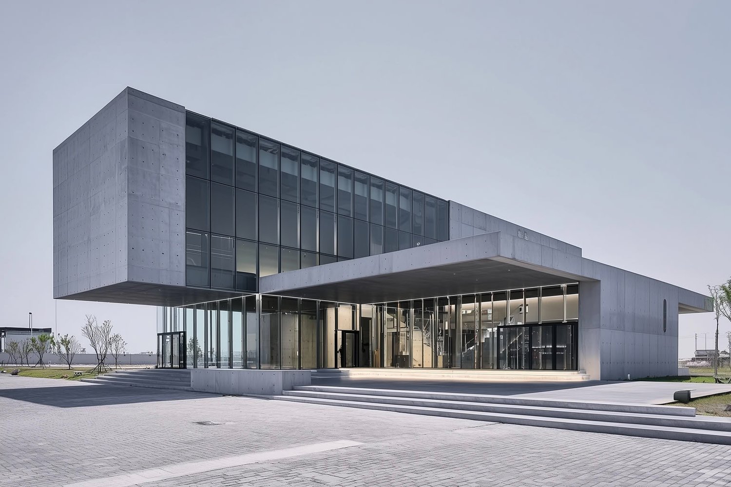 Modern building with cantilevered concrete forms, expansive glass facade, and a wide entrance.