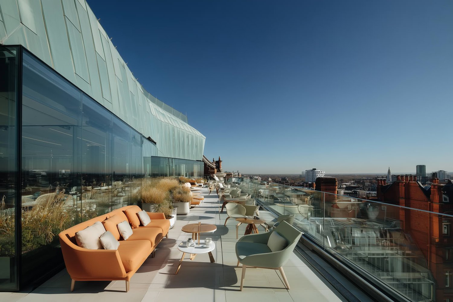Modern rooftop terrace with orange and green seating, glass walls, and a city view.