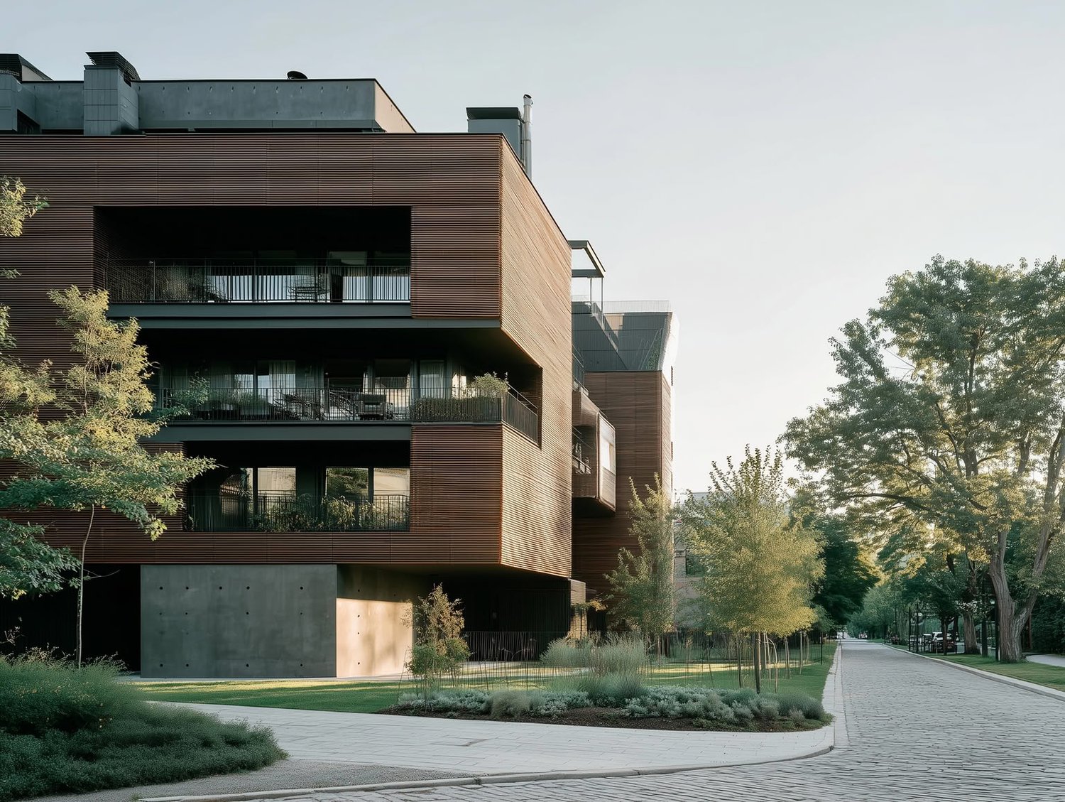 Modern building with warm wooden slat cladding, dark balconies, large glass windows, and concrete base next to a cobblestone path and trees.