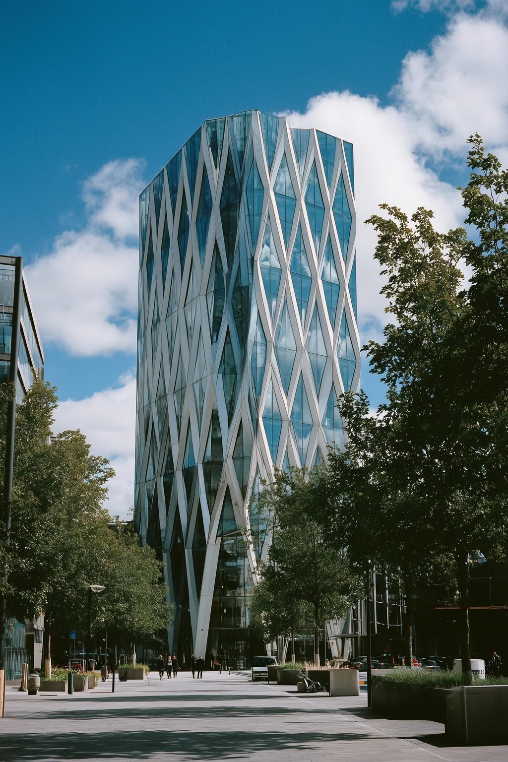 Modern glass skyscraper with a white diamond facade reflecting a blue sky and clouds.