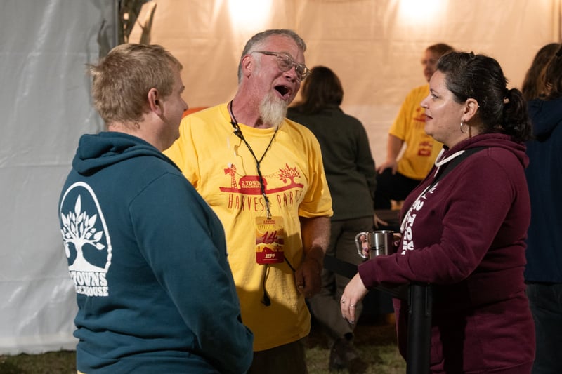 Three attendees engaging in conversation at Harvest Party 2024.