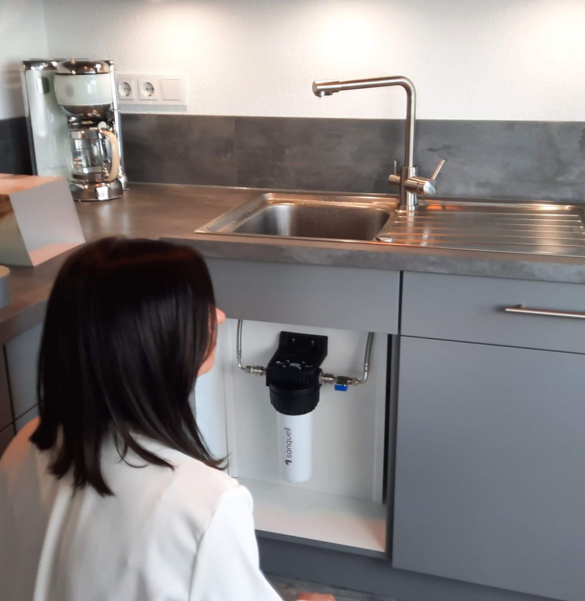 Untertisch-Kalkfilter im geöffneten Spülenschrank einer Küche