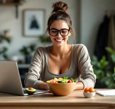 Eine Frau sitzt am Computer. Es steht eine Bowl-Schale mit gesundem Mittagessen auf dem Tisch