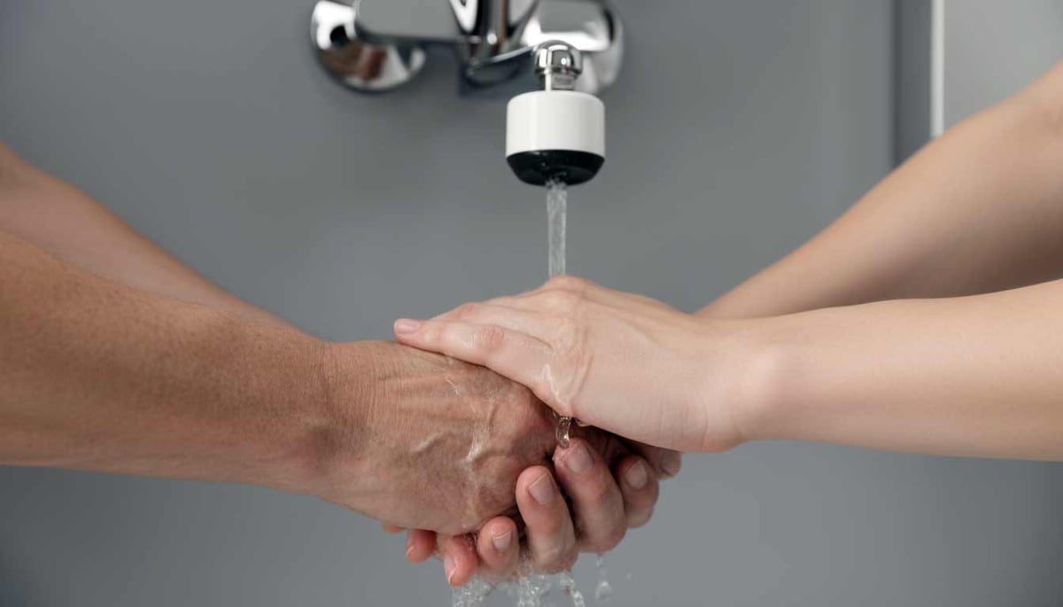 Hände werden unter einem Wasserhahn mit aufgesetztem Sterilfilter gewaschen