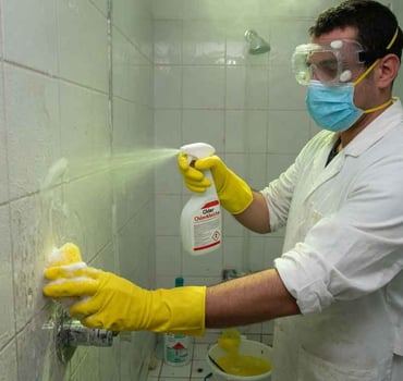 Ein Mann reinigt die Dusche mit Chlor