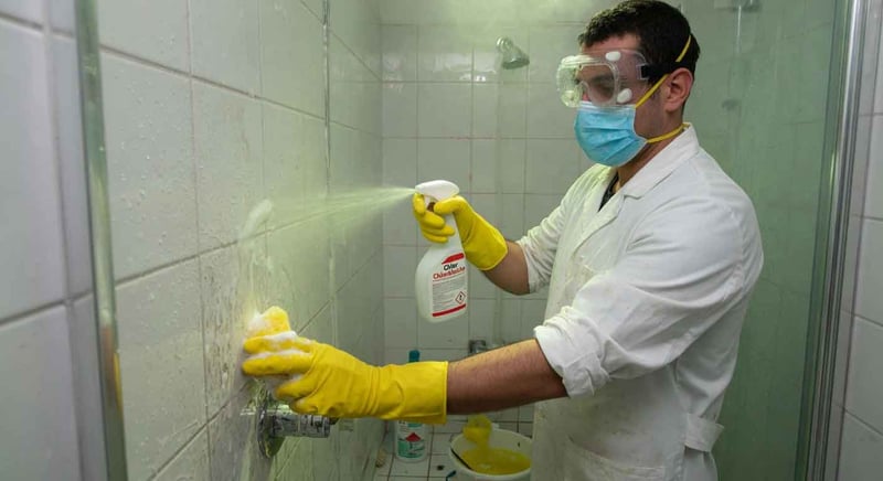 Ein Mann reinigt die Dusche mit Chlor