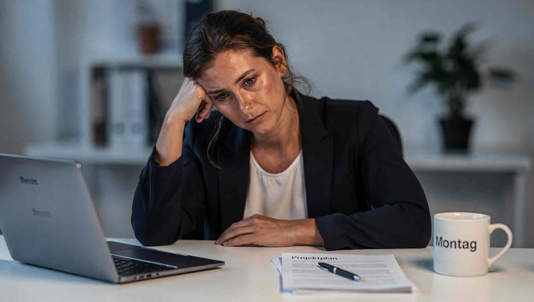 Frau sitzt müde am Schreibtisch