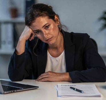 Frau sitzt müde am Schreibtisch
