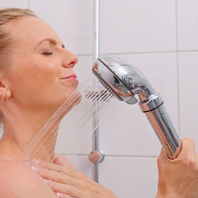 Frau duscht mit dem Safety Chrom, der Strahl tritt gebündelt aus