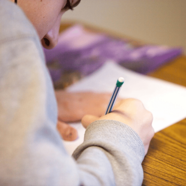Student writing at a desk, utilizing resources funded by Title I