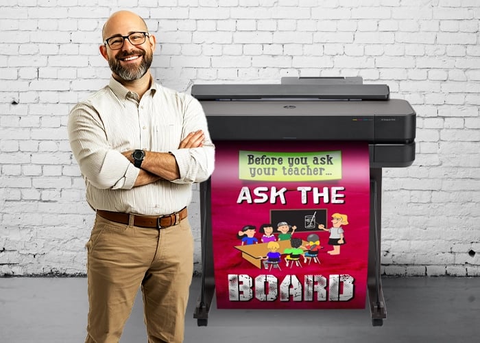 Teacher standing next to a poster maker machine with a colorful printed poster