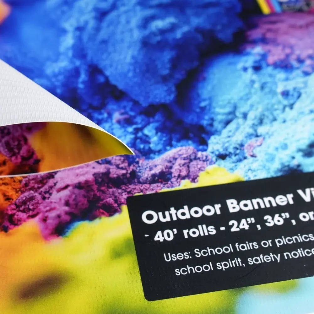 Close-up of colorful outdoor banner material with a sample label showcasing size and printing options.