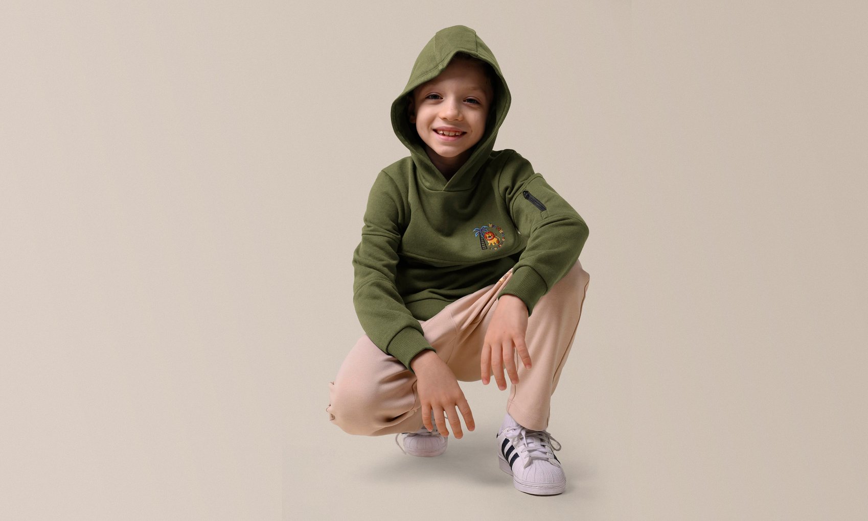 A young boy in a stylish green embroidery print hoodie with joggers from Enorsia.