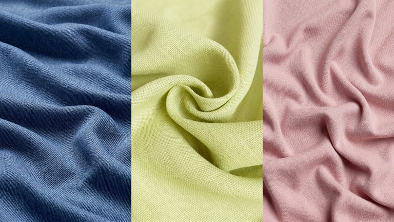 A close-up of natural linen, cotton, and sustainable fabrics in warm summer light - ENORSIA