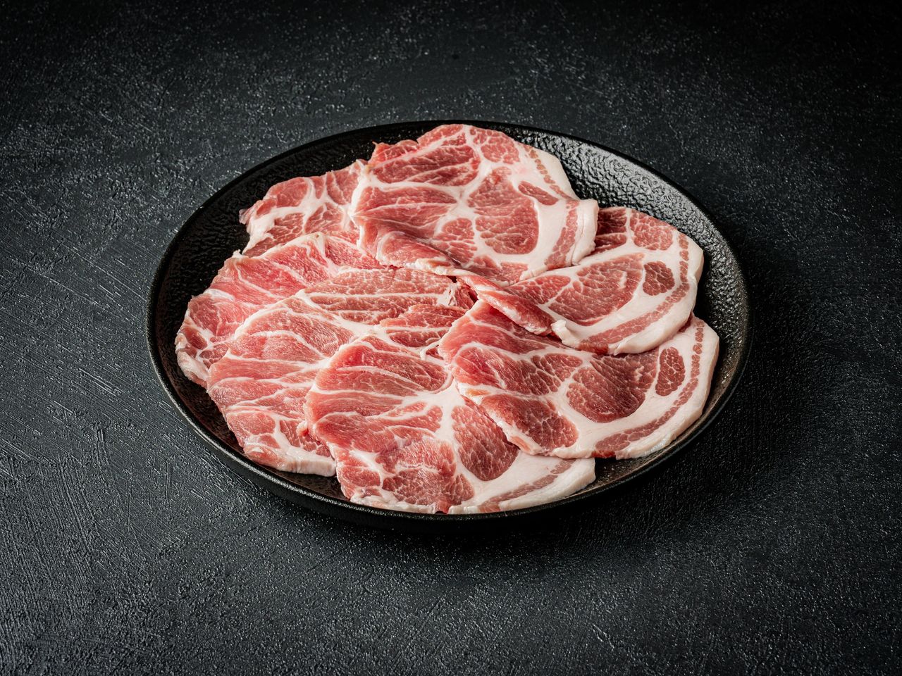 대지안집 메뉴 촬영 - 다크 텍스처 배경 위 검은 무광 접시에 담은 돼지고기 부위 단품
