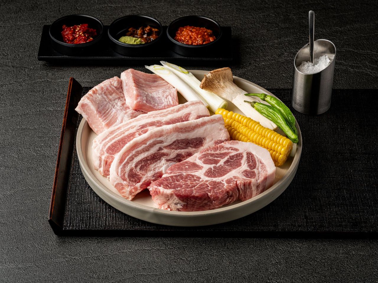 마장동김씨 메뉴 촬영 - 크림색 접시에 담은 삼겹살 생고기 단품, 다크 슬레이트 배경