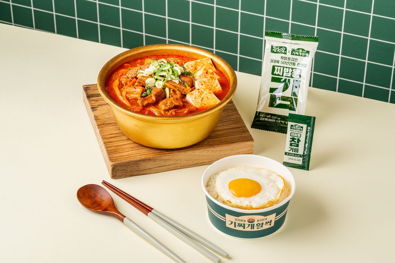 기찌개활짝 배달앱 촬영 - 초록 타일 벽 앞 나무 받침 위 금빛 양은냄비 김치찌개와 달걀프라이 밥