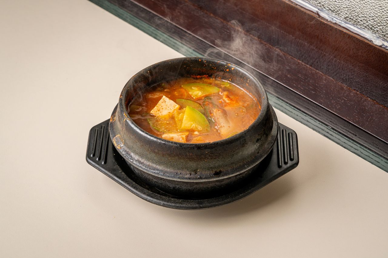 지대로 맛돼지 메뉴판 촬영 - 창가 원목 문틀을 배경으로 김이 오르는 뚝배기 찌개 단품컷