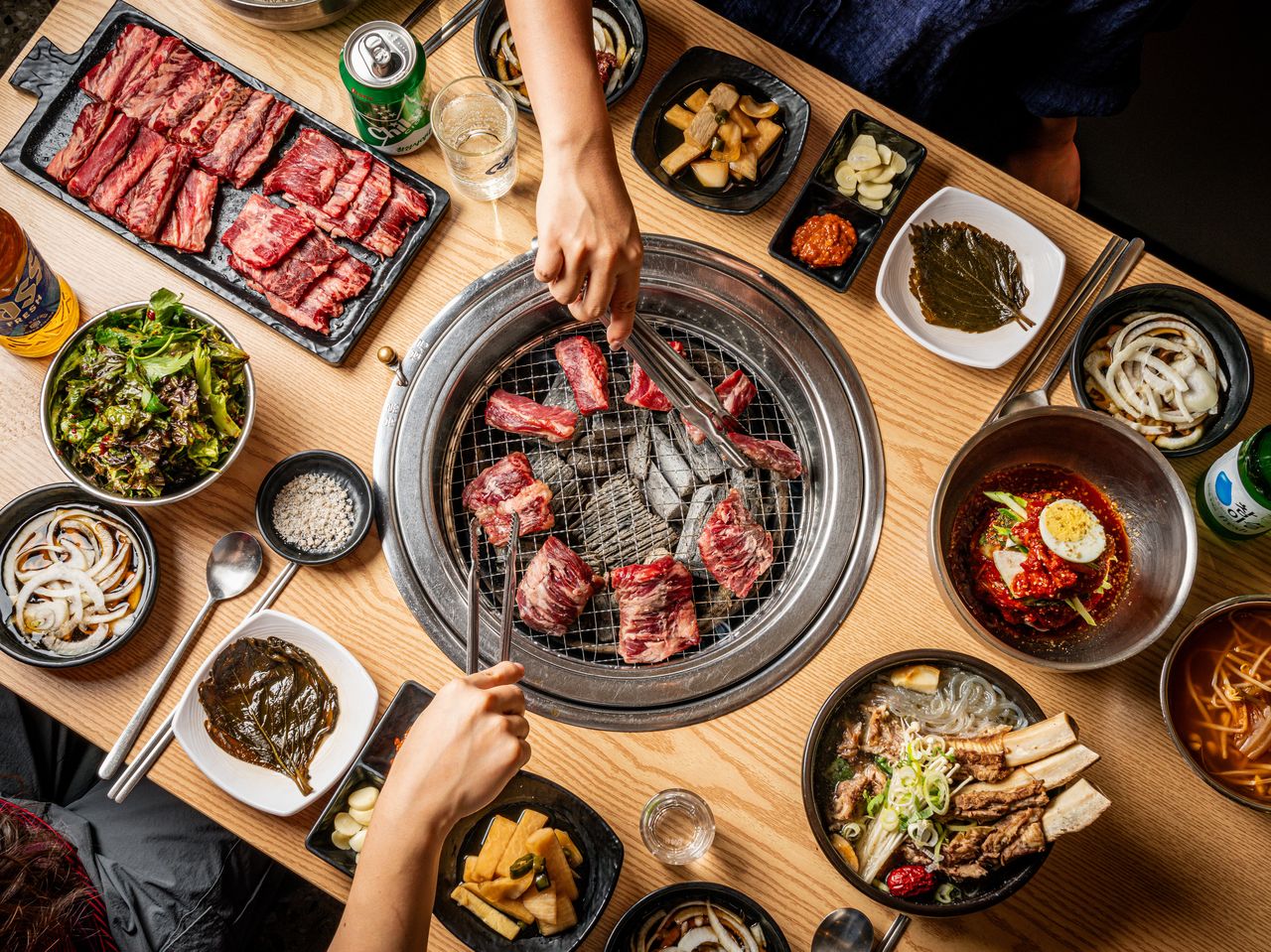 고기집 연출 촬영 - 정면 위에서 내려다본 숯불 석쇠와 원육 보드, 쌈채소, 냉면, 갈비탕이 펼쳐진 가로 탑뷰