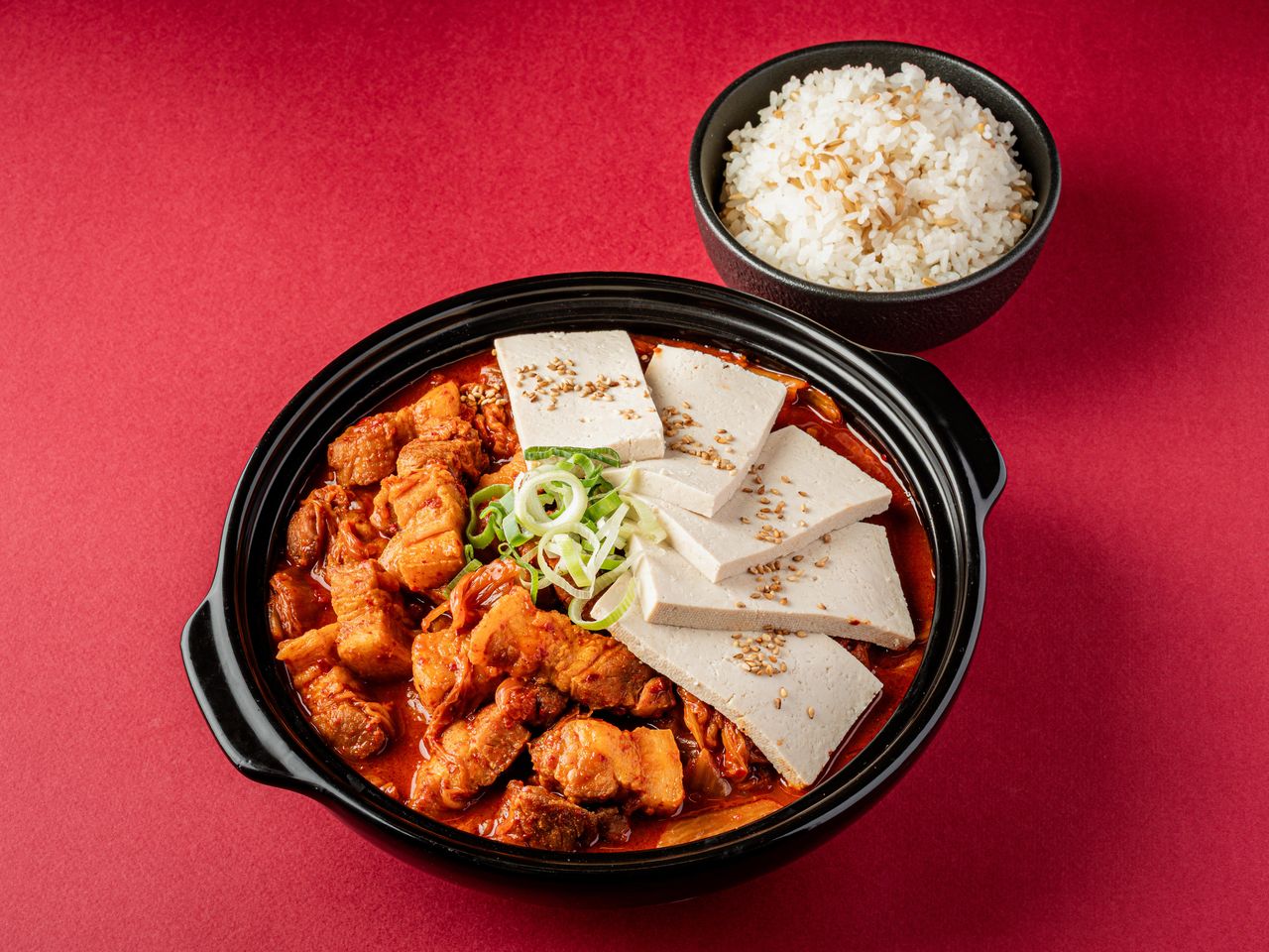 수유 배달 한식 메뉴사진 촬영 - 고기와 김치가 든 빨간 찌개 위에 두부 다섯 조각을 부채꼴로 겹치고 곡물 섞인 밥 공기를 곁들인 컷