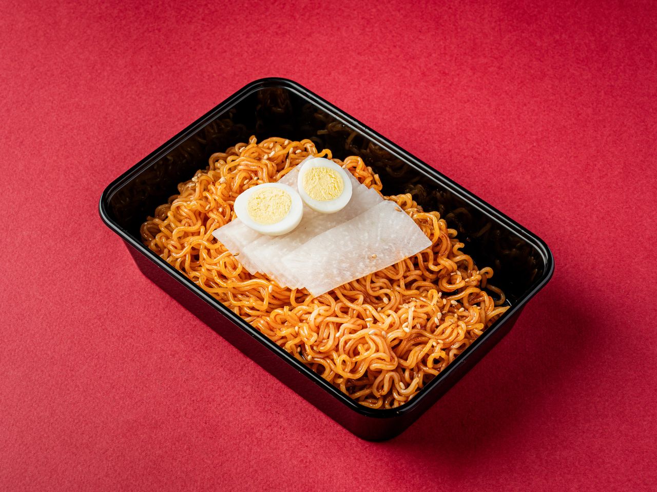 수유 배달 한식 메뉴사진 촬영 - 검은 사각 배달 용기에 양념 면과 얇게 썬 무, 반으로 자른 삶은 달걀을 올린 단품