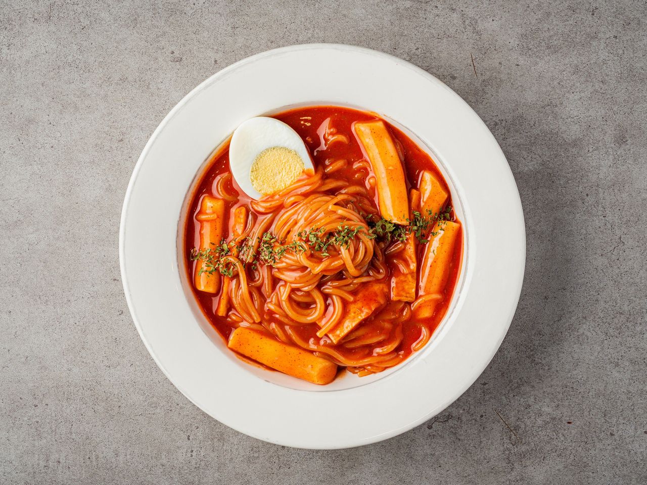 정성한줄 아현점 배달음식 촬영 - 회색 콘크리트 배경 위 흰 접시에 담은 라볶이 탑뷰