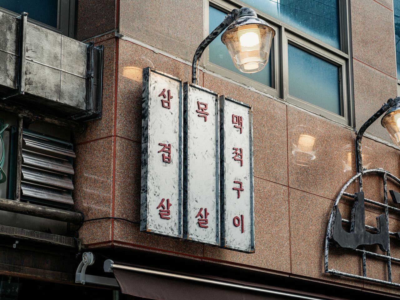산솔 신사본점 매장 사진 촬영 - 붉은 화강석 벽에 세로로 걸린 삼겹살·목살·맥적구이 세 칸 간판과 갓등