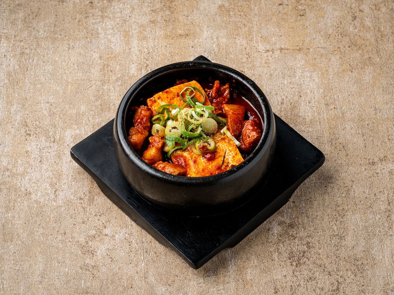 산솔 신사본점 메뉴 촬영 - 검은 받침 위 뚝배기에 담긴 두부와 고기가 든 빨간 찌개