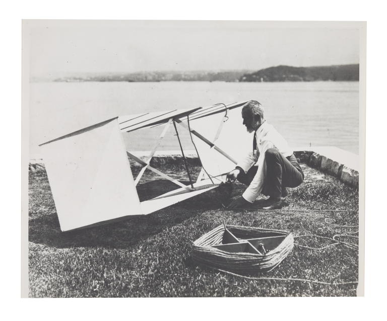 Photograph of Lawrence Hargrave kneeling beside box kite at Woollahra Point