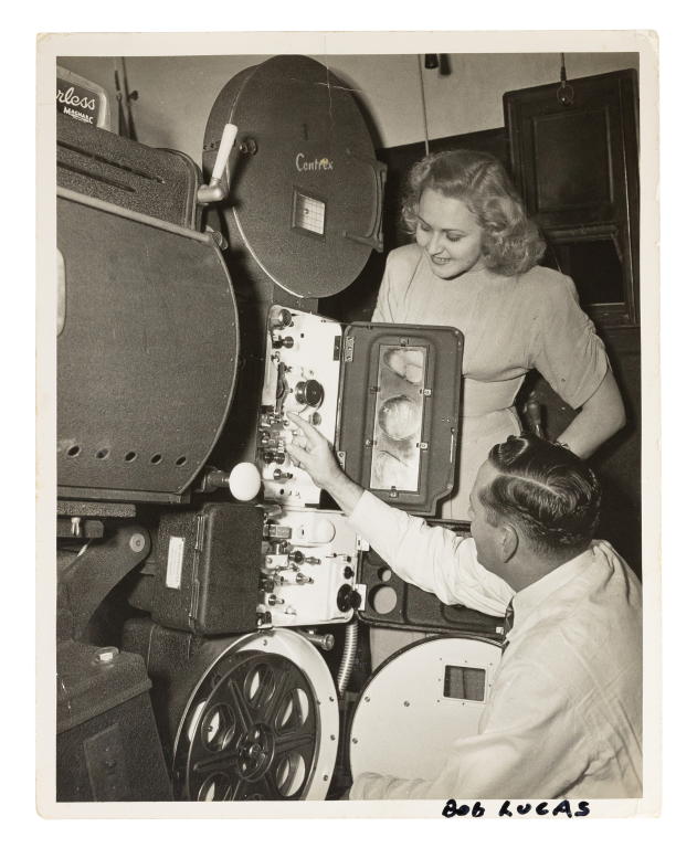 Photograph of R.J. (Bob) Lucas and unidentified woman looking at a Centrex projector