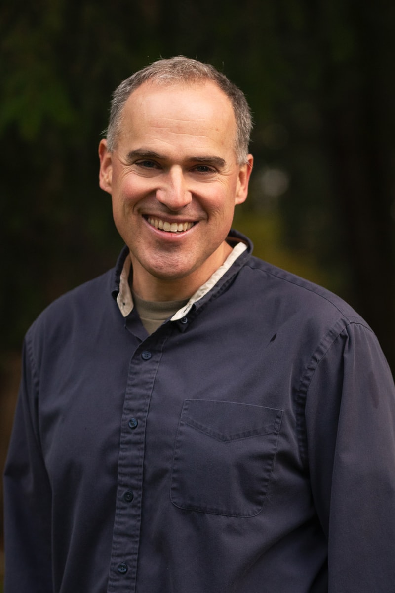 Headshot of a smiling man in a dark shirt