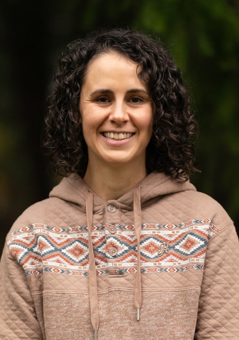 Headshot of a woman with curly hair wearing a patterned hoodie