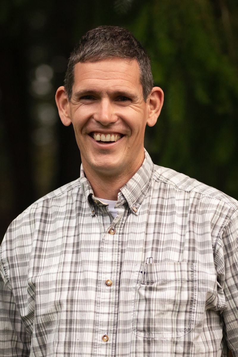 Headshot of a man smiling in a plaid shirt