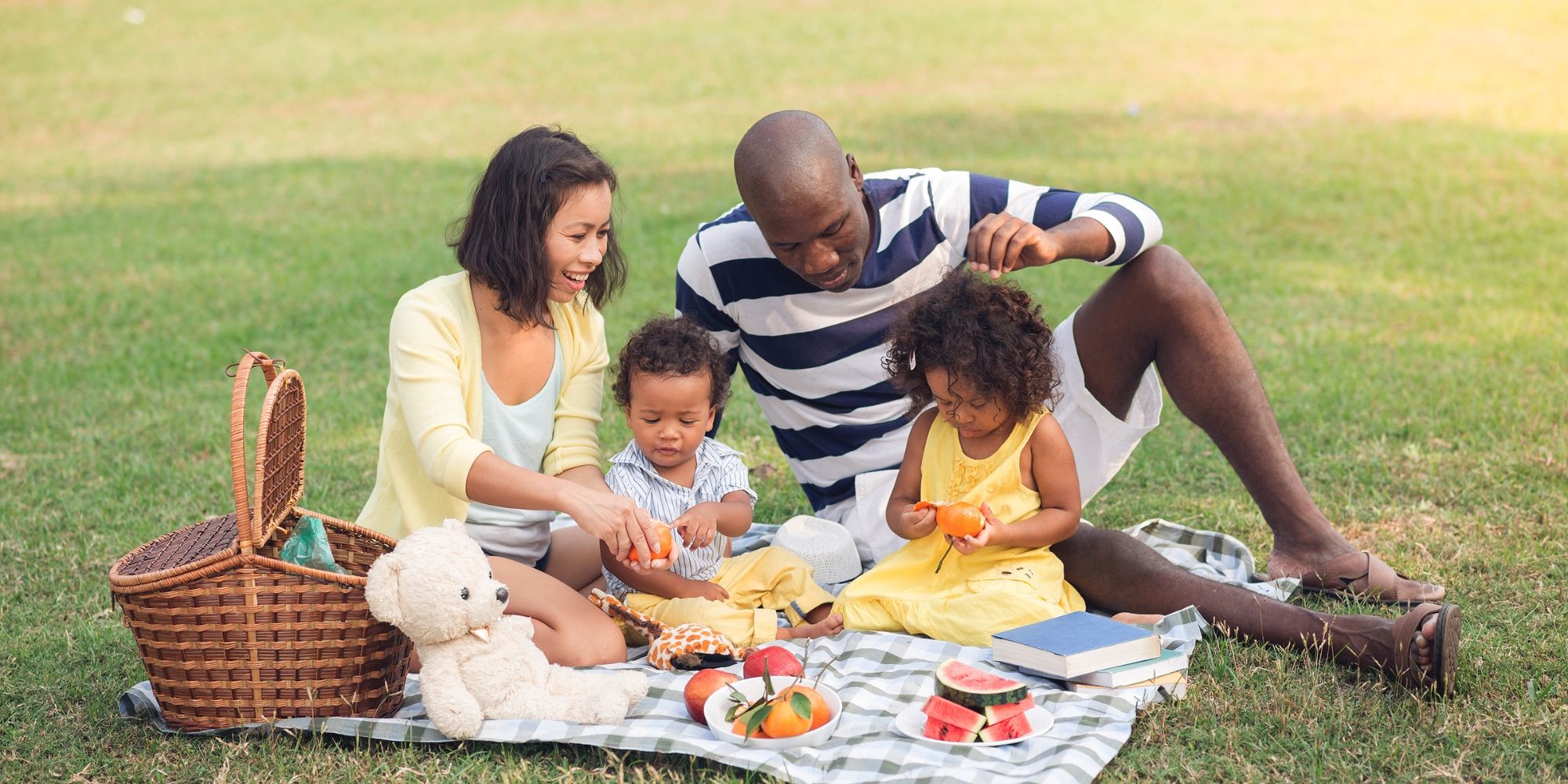Families share a picnic together on the grass.