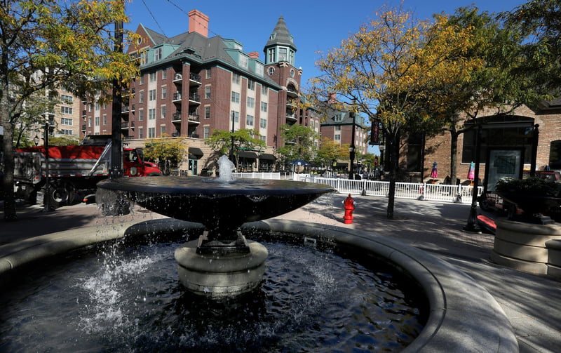 Downtown Arlington Heights, Illinois, with a red-brick clock-tower building beside a plaza and fountain.