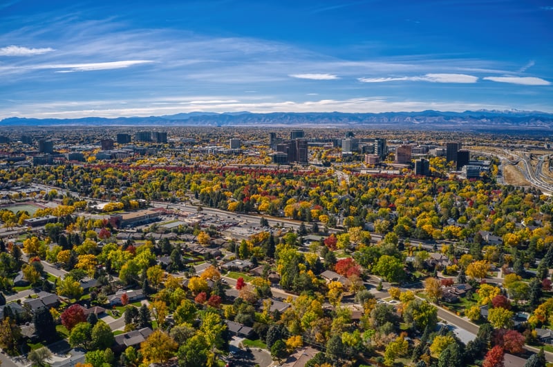 Aerial view of Aurora, Colorado, with autumn neighborhoods, office buildings and mountains beyond.