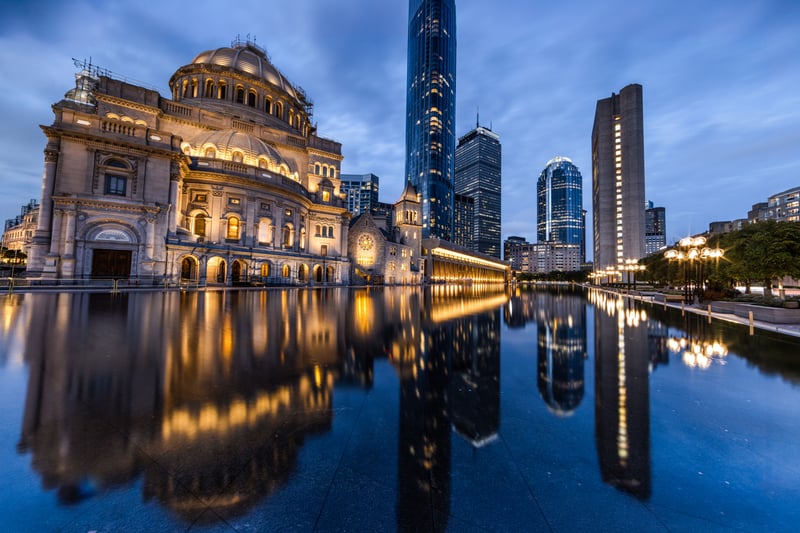 Boston's First Church of Christ, Scientist and surrounding skyline reflected in the plaza pool at dusk.