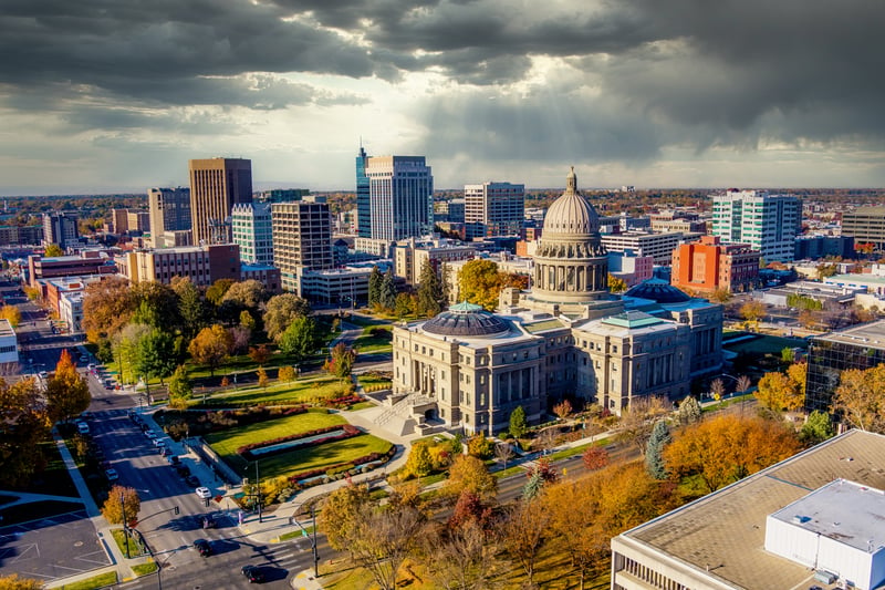 Downtown Boise, Idaho, with the Idaho State Capitol and autumn trees beneath a cloudy sky.
