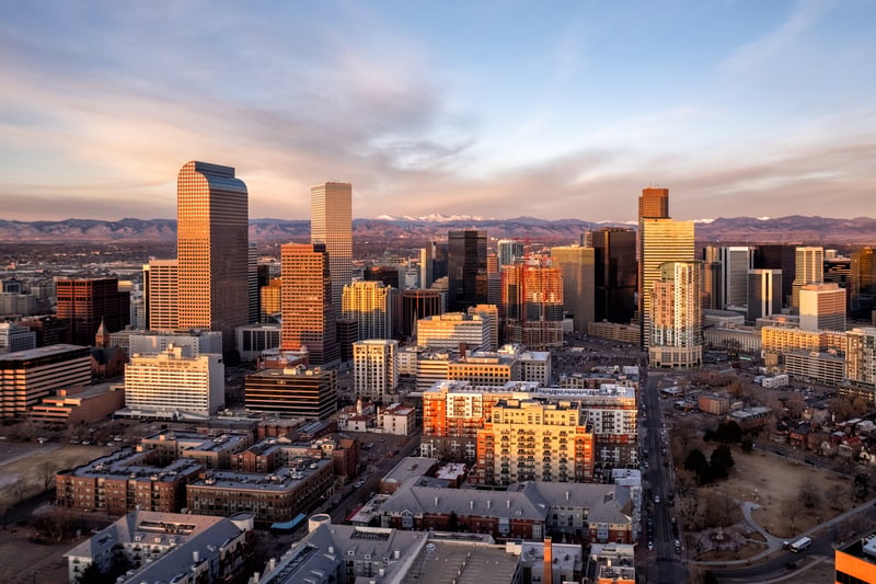 Aerial view of downtown Denver, Colorado, with high-rise buildings and neighborhoods beyond.